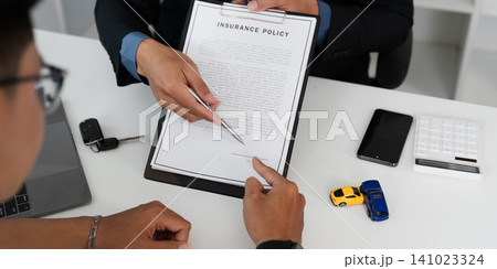 Car insurance policy signing concept with agent pointing at contract on desk 141023324