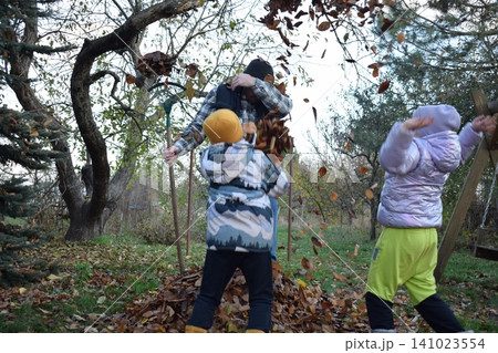 Young father, pre-teen daughter and son in warm autumn clothes spending quality time together among fallen leaves. Happy family enjoying the beauty of fall, playful moments and family life outdoors Young father, pre-teen daughter and son in warm autumn clothes spending quality time together among fallen leaves. Happy family enjoying the beauty of fall, playful moments and family life outdoors 141023554