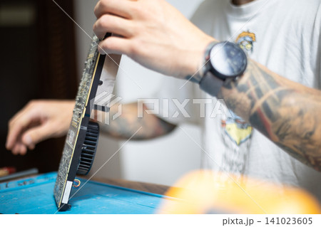 Technician works on computer hardware in a workshop during the day Technician works on computer hardware in a workshop during the day 141023605