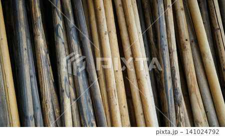 Stacked natural round wooden logs and timber poles 141024792