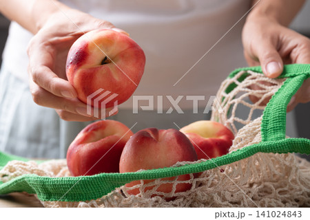 Fresh white peach in mesh bag holding by woman hand, Summer fruit Fresh white peach in mesh bag holding by woman hand, Summer fruit 141024843