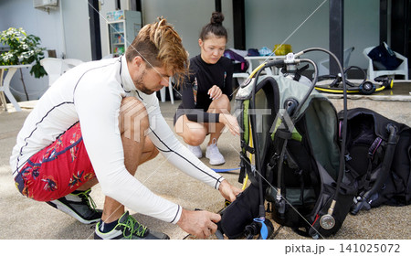 The dive instructor provides equipment instruction to the young woman before training begins. The dive instructor provides equipment instruction to the young woman before training begins. 141025072