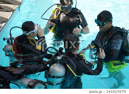 Professional scuba diver instructs the novice how to use the equipment before dive Professional scuba diver instructs the novice how to use the equipment before dive 141025079