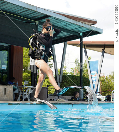 A professional diver and a novice practice diving in a pool. A professional diver and a novice practice diving in a pool. 141025090