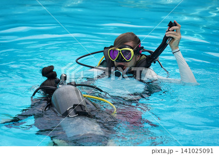 A professional diver and a novice practice diving in a pool. A professional diver and a novice practice diving in a pool. 141025091