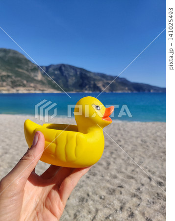 rubber toy yellow duck in hand with a view of the sea 141025493