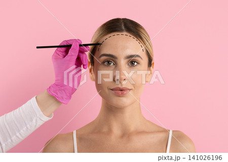 Womans forehead marked with dashed line by gloved hand holding pencil Womans forehead marked with dashed line by gloved hand holding pencil 141026196