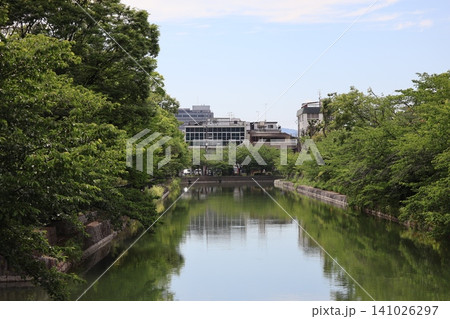緑の木々と建物と空の映る水面の疏水のある町並みの風景 緑の木々と建物と空の映る水面の疏水のある町並みの風景 141026297