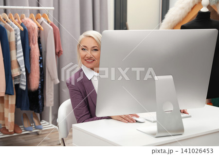 Female business owner working with computer in boutique 141026453