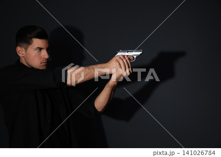 Professional killer with gun on black background Professional killer with gun on black background 141026784