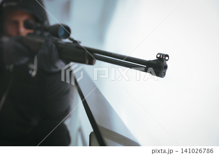 Hired professional killer indoors, focus on sniper rifle Hired professional killer indoors, focus on sniper rifle 141026786