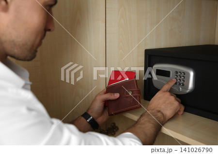 Man opening black steel safe with electronic lock at hotel, closeup 141026790