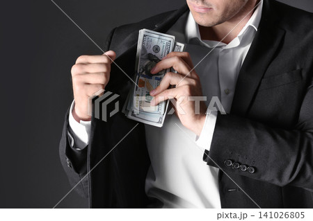 Man putting bribe money into pocket on black background, closeup Man putting bribe money into pocket on black background, closeup 141026805