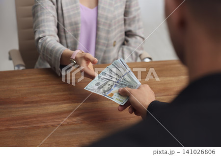 Man giving bribe money to woman at table indoors, closeup Man giving bribe money to woman at table indoors, closeup 141026806