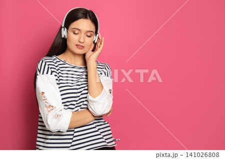 Young woman listening to audiobook on pink background. Space for text Young woman listening to audiobook on pink background. Space for text 141026808