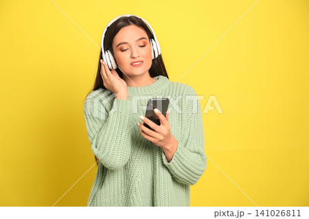 Young woman listening to audiobook on yellow background Young woman listening to audiobook on yellow background 141026811