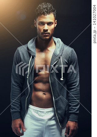 Fitness, portrait and man in studio with stomach muscle, confidence and workout routine in health, wellness and power. Hoodie, pride and strong athlete on black background for exercise, body and care 141027004