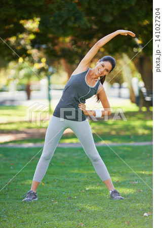 Portrait, woman and happy with headphones for stretching, exercise and podcast for training motivation. Female person, smile and fitness in park with balance warm up, wellness and music in earphones Portrait, woman and happy with headphones for stretching, exercise and podcast for training motivation. Female person, smile and fitness in park with balance warm up, wellness and music in earphones 141027204