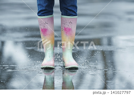 Woman in rubber boots walking outdoors on rainy day, closeup Woman in rubber boots walking outdoors on rainy day, closeup 141027797