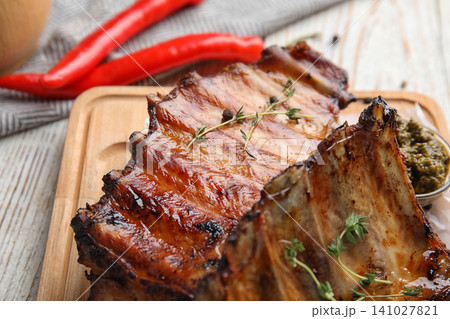 Tasty grilled ribs with thyme on white wooden table, closeup Tasty grilled ribs with thyme on white wooden table, closeup 141027821