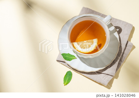 A cup of hot tea with fresh lemon and mint on a bright yellow background A cup of hot tea with fresh lemon and mint on a bright yellow background 141028046