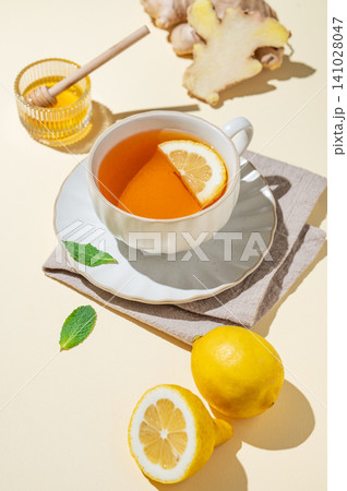 A cup of hot tea with fresh lemon, ginger, mint on a bright yellow background 141028047