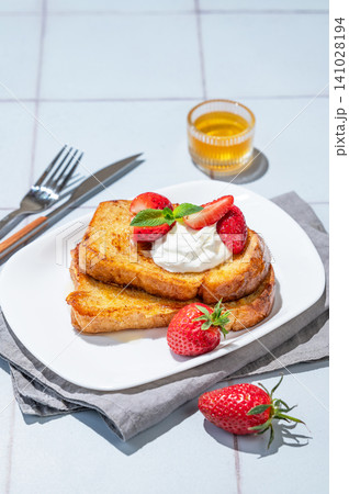 Brioche toasts with strawberries and whipped cream, drizzled with honey on a plate Brioche toasts with strawberries and whipped cream, drizzled with honey on a plate 141028194