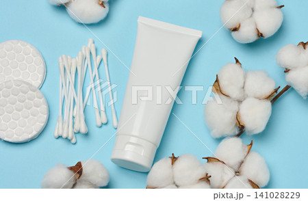 White tube, cotton pads and cotton flowers on a blue background, top view, concept of a set of natural cosmetics 141028229