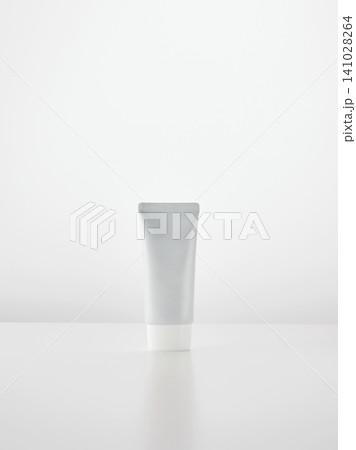 An empty white plastic tube for cosmetic cream stands on a white surface against a light background An empty white plastic tube for cosmetic cream stands on a white surface against a light background 141028264