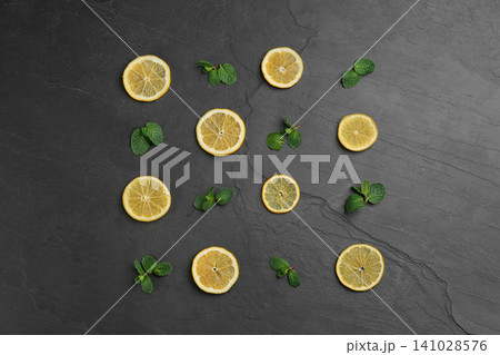 Lemonade layout with juicy lemon slices and mint on black table, top view Lemonade layout with juicy lemon slices and mint on black table, top view 141028576