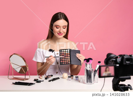 Beauty blogger recording makeup tutorial on pink background 141028633