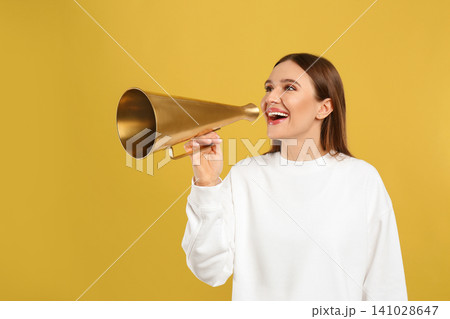 Young woman with vintage megaphone on yellow background 141028647