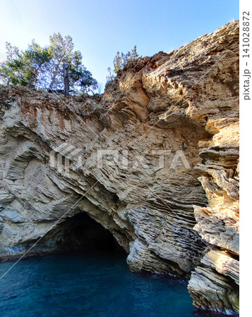 a large cave on the seashore is washed by water a large cave on the seashore is washed by water 141028872