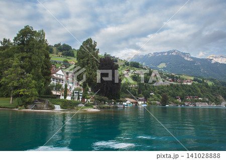 Scenic lakeside villas and lush green hills on the shores of Lake Thun in Switzerland Scenic lakeside villas and lush green hills on the shores of Lake Thun in Switzerland 141028888