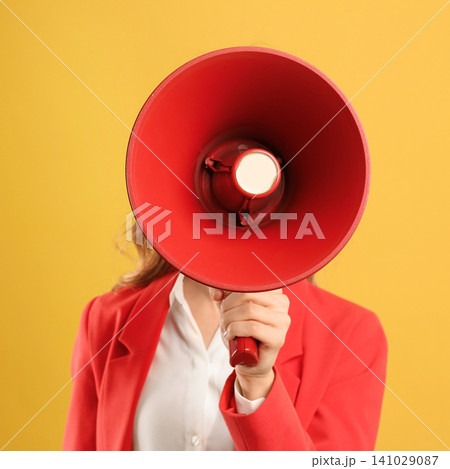 Young woman with megaphone on yellow background 141029087