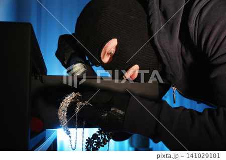 Thief taking jewelry out of steel safe indoors at night Thief taking jewelry out of steel safe indoors at night 141029101
