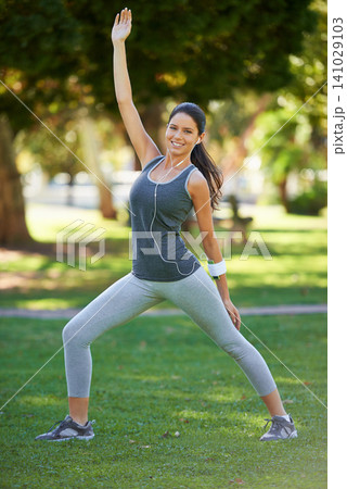 Woman, portrait and headphones with stretching in park for training, warm up and workout music. Female person, earphones and athlete in nature with balance, exercise and podcast for motivation 141029103