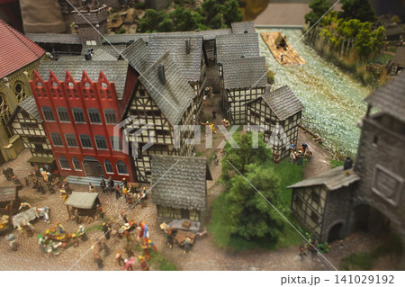 Miniature medieval town square with a bustling market and red guildhall 141029192