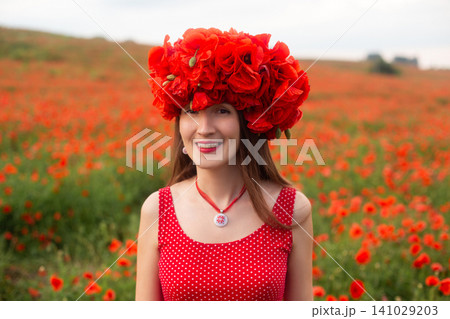Smiling woman in red polka dot dress and poppy wreath in flower field Smiling woman in red polka dot dress and poppy wreath in flower field 141029203