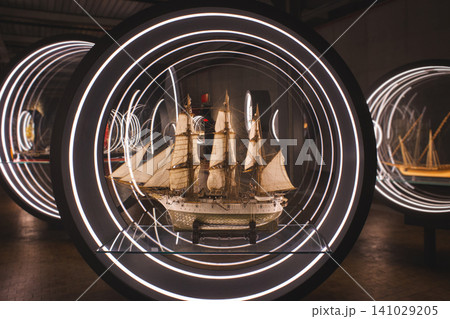 Exquisite detailed model of a historic sailing ship displayed inside a futuristic circular neon glass case Exquisite detailed model of a historic sailing ship displayed inside a futuristic circular neon glass case 141029205