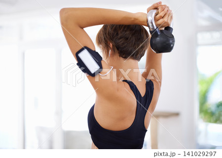 Home, gym or woman with fitness, kettlebell or music for strength training, workout or exercise. Healthy, sports or back of female person with weight or strong arms streaming podcast audio or radio Home, gym or woman with fitness, kettlebell or music for strength training, workout or exercise. Healthy, sports or back of female person with weight or strong arms streaming podcast audio or radio 141029297