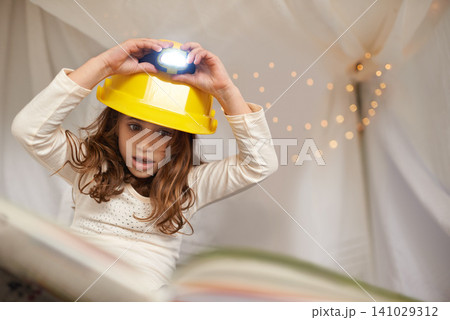 Girl, child and book for reading with lamp, below and learning with thinking for education in family home. Kid, story and study with light on helmet, language or literacy skills with blanket in house Girl, child and book for reading with lamp, below and learning with thinking for education in family home. Kid, story and study with light on helmet, language or literacy skills with blanket in house 141029312