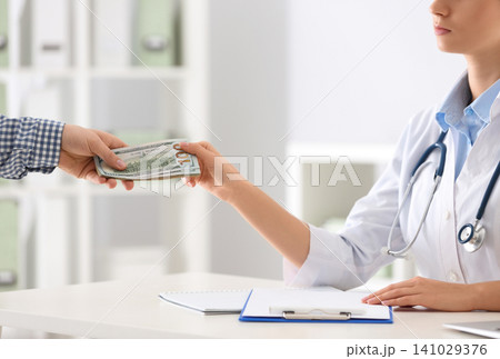 Patient giving bribe to doctor in clinic, closeup. Corrupted medicine Patient giving bribe to doctor in clinic, closeup. Corrupted medicine 141029376