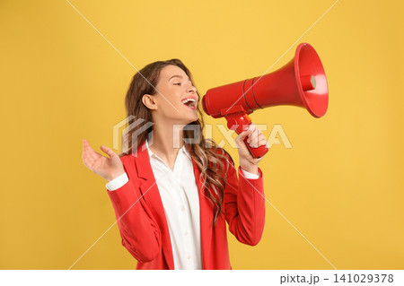 Young woman with megaphone on yellow background 141029378