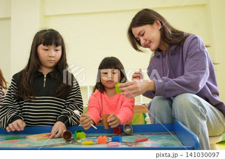 The teacher is teaching young children in a class at school. The teacher is teaching young children in a class at school. 141030097