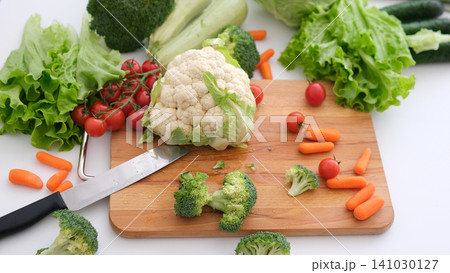 Chopped broccoli and other vegetables on wooden cutting board. 141030127