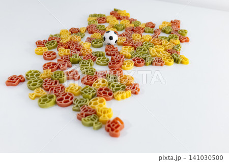 Colorful pasta pieces with football themed shapes outlining the silhouette of Germany, creating playful football themed food art. 141030500