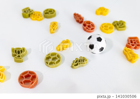 Colorful pasta pieces with football themed shapes and a small soccer ball scattered on a surface, creating child friendly food art Colorful pasta pieces with football themed shapes and a small soccer ball scattered on a surface, creating child friendly food art 141030506
