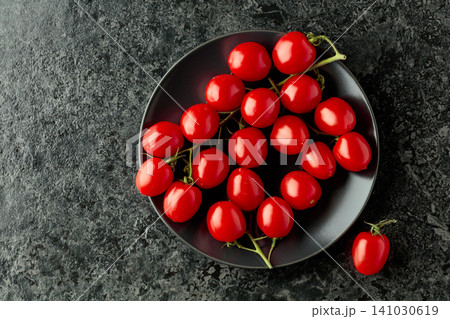 Small red cherry tomatoes on a black plate. 141030619