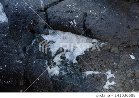 A close-up of a white quartz vein embedded in a dark porous volcanic rock surface A close-up of a white quartz vein embedded in a dark porous volcanic rock surface 141030689